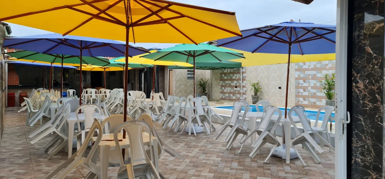 Área externa do Lar dos Sonhos com mesas, guarda-sóis e piscina